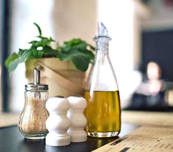 A stylish table arrangement with olive oil, spices, and green plant for a cozy dining ambiance.